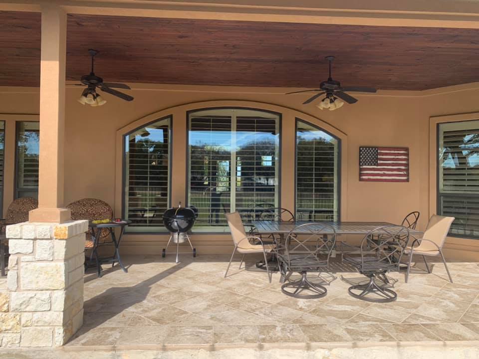 Covered outdoor dining area complete with a wooden ceiling, large windows, and comfortable seating, perfect for dining al fresco while enjoying the view.