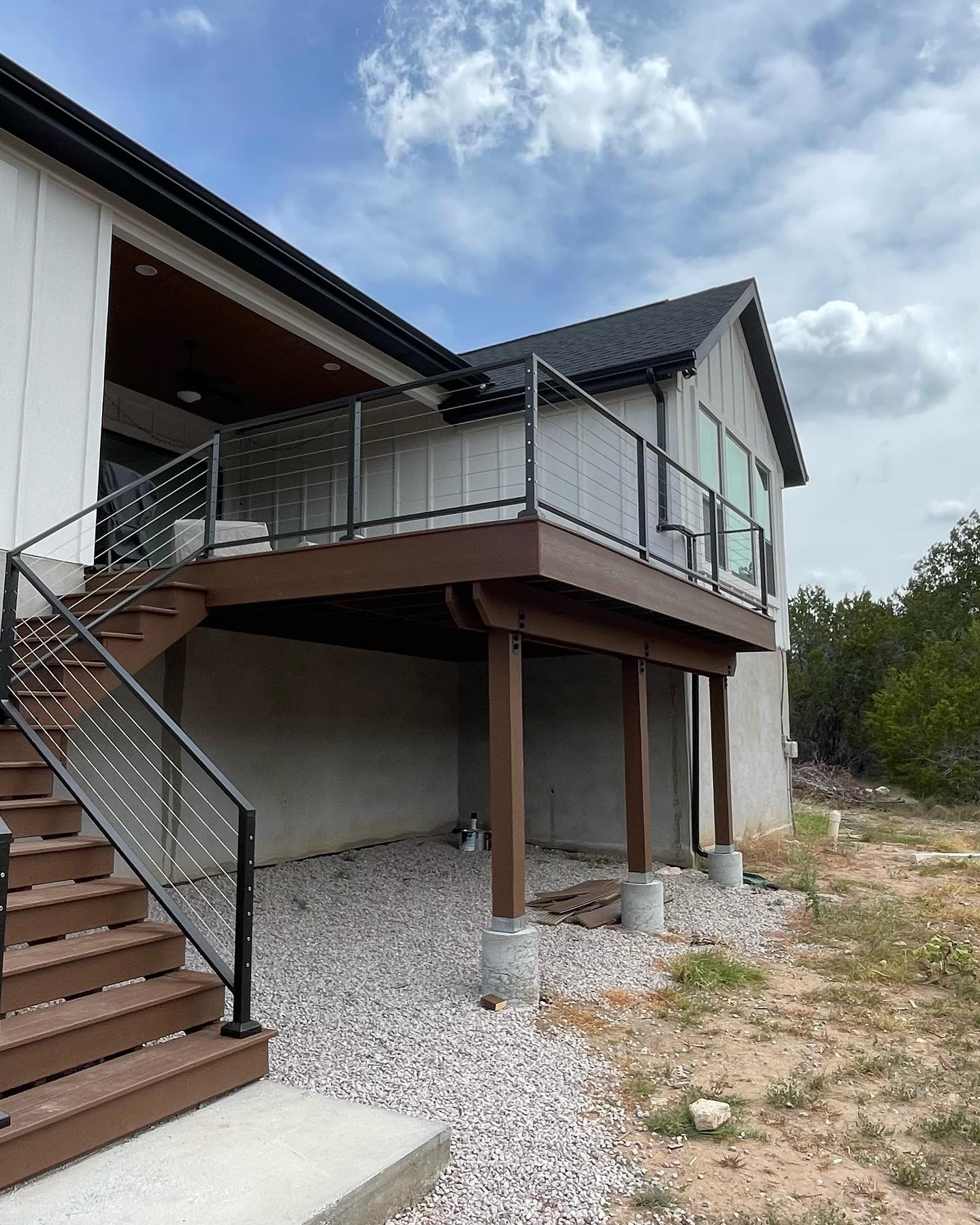 A stylish exterior of a home featuring a raised deck with metal railings, surrounded by natural views, integrating modern design with outdoor living.