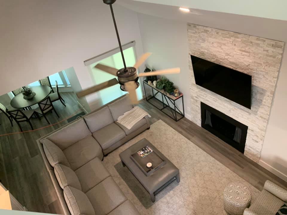 An elegant open plan living area with high ceilings, modern furniture, and a stone fireplace, ideal for spacious and stylish living.